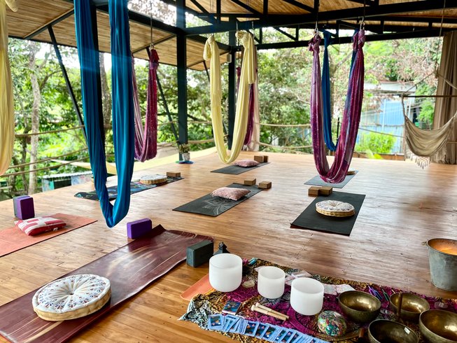 Open-air aerial yoga shala at a Costa Rica retreat near Tamarindo with hammocks, mats, and sound healing bowls.