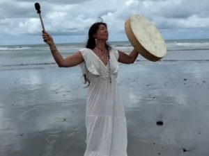 Facilitator leading a sacred drum ceremony on a Costa Rica beach during an ancestral medicine retreat.