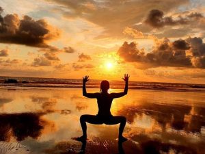 Person practicing yoga on the beach at sunrise during a private ancestral medicine retreat in Costa Rica.