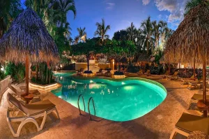 Lagoon-style tropical swimming pool illuminated at night at a luxury Costa Rica wellness retreat.