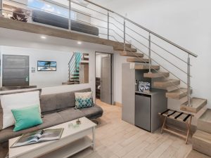 Modern loft-style accommodation with living area and staircase at a surf camp retreat in Tamarindo, Costa Rica.