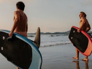 Surfers carrying boards along the beach before a surf session at Tamarindo Beach, Costa Rica.