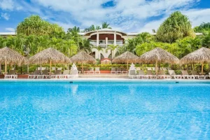 Large resort swimming pool surrounded by palm trees and lounge chairs in Tamarindo, Costa Rica.