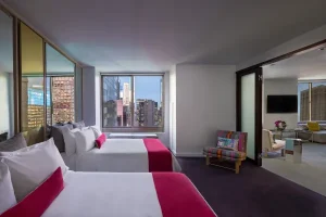 Modern guest room with city skyline views at W New York Times Square hotel.