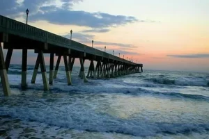 Ocean pier extending into the Atlantic Ocean near Wilmington, North Carolina at sunset.